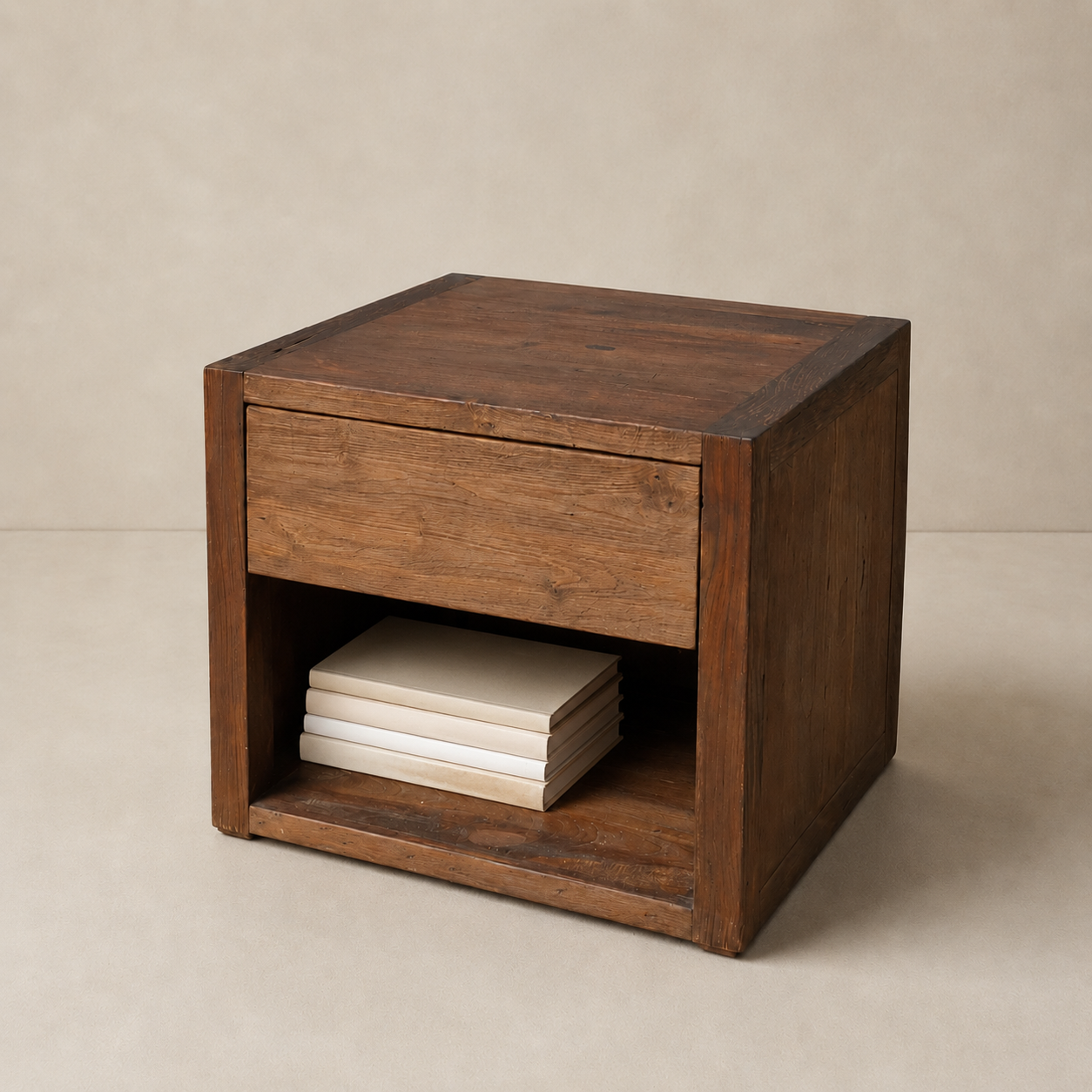 A rustic dark brown wooden nightstand with a single drawer and an open shelf holding a stack of neutral-colored books, set against a warm beige background.