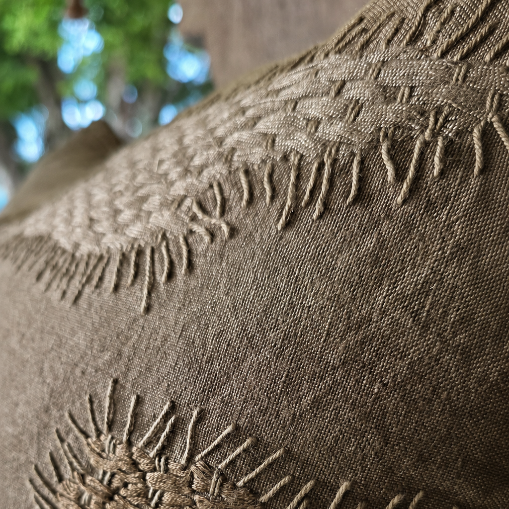 A close-up of a olive brown woven textile with two embroidered patterns and fringed edges, understated texture, relaxed byron bay feel