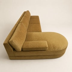 A modern retro inspired L-shaped sectional sofa upholstered in a textured mustard-yellow fabric, photographed from a high-angle perspective against a plain off-white background.