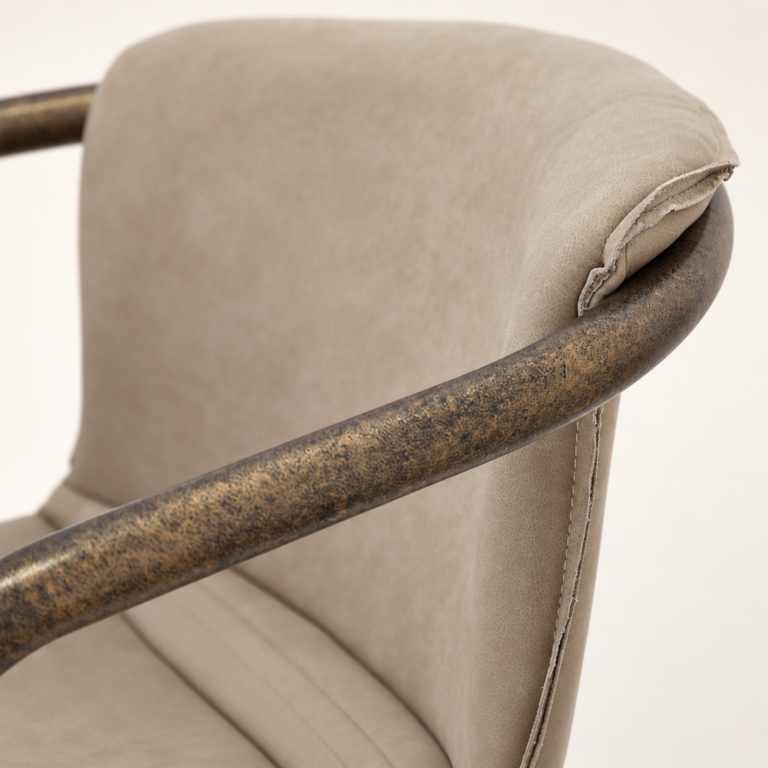 Close-up detail of a chair showing a curved upholstered backrest in a light beige fabric and a distressed bronze metal armrest.