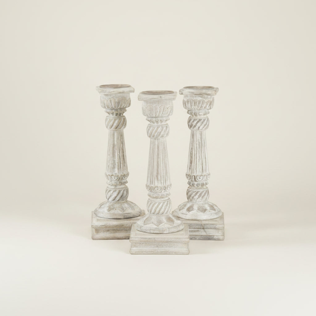 Three decorative candle holders on a textured wall.