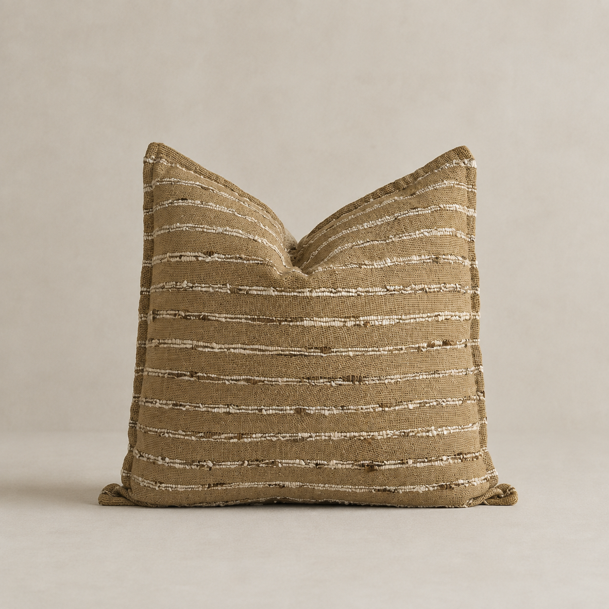 A square decorative throw pillow in a textured tan fabric with horizontal beige and white stripe details, set against a neutral beige background.