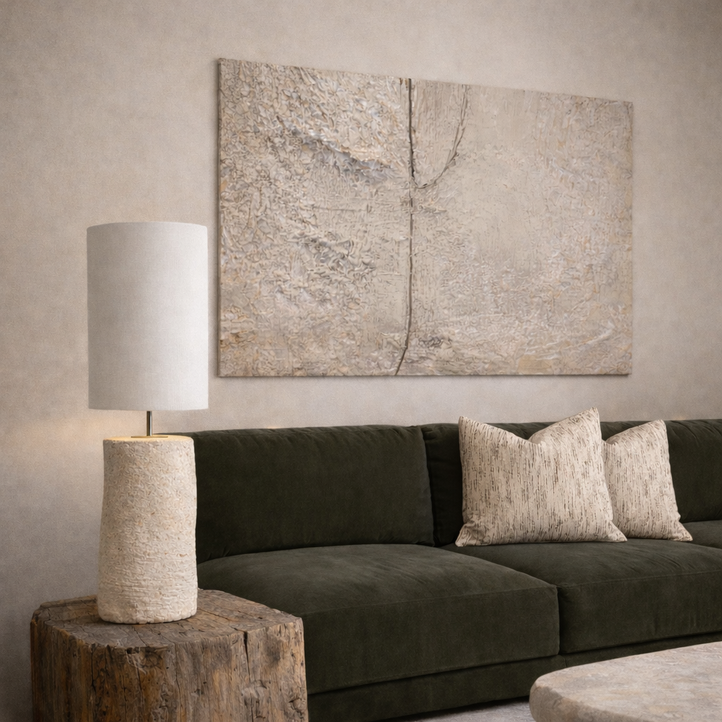 Living room with dark green sofa, textured wall art, and lamp on a wooden side table and an Alba table lamp by Bisque Traders.