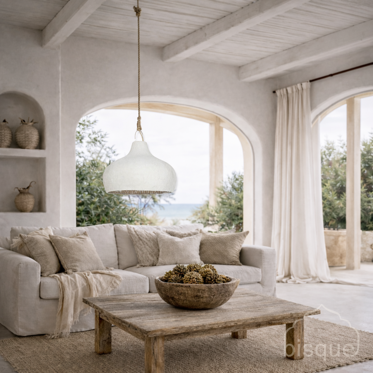 Cozy living room with the Aquarius fishtrap rattan and clay pendant light hanging over a beige sofa, wooden coffee table, and large windows.
