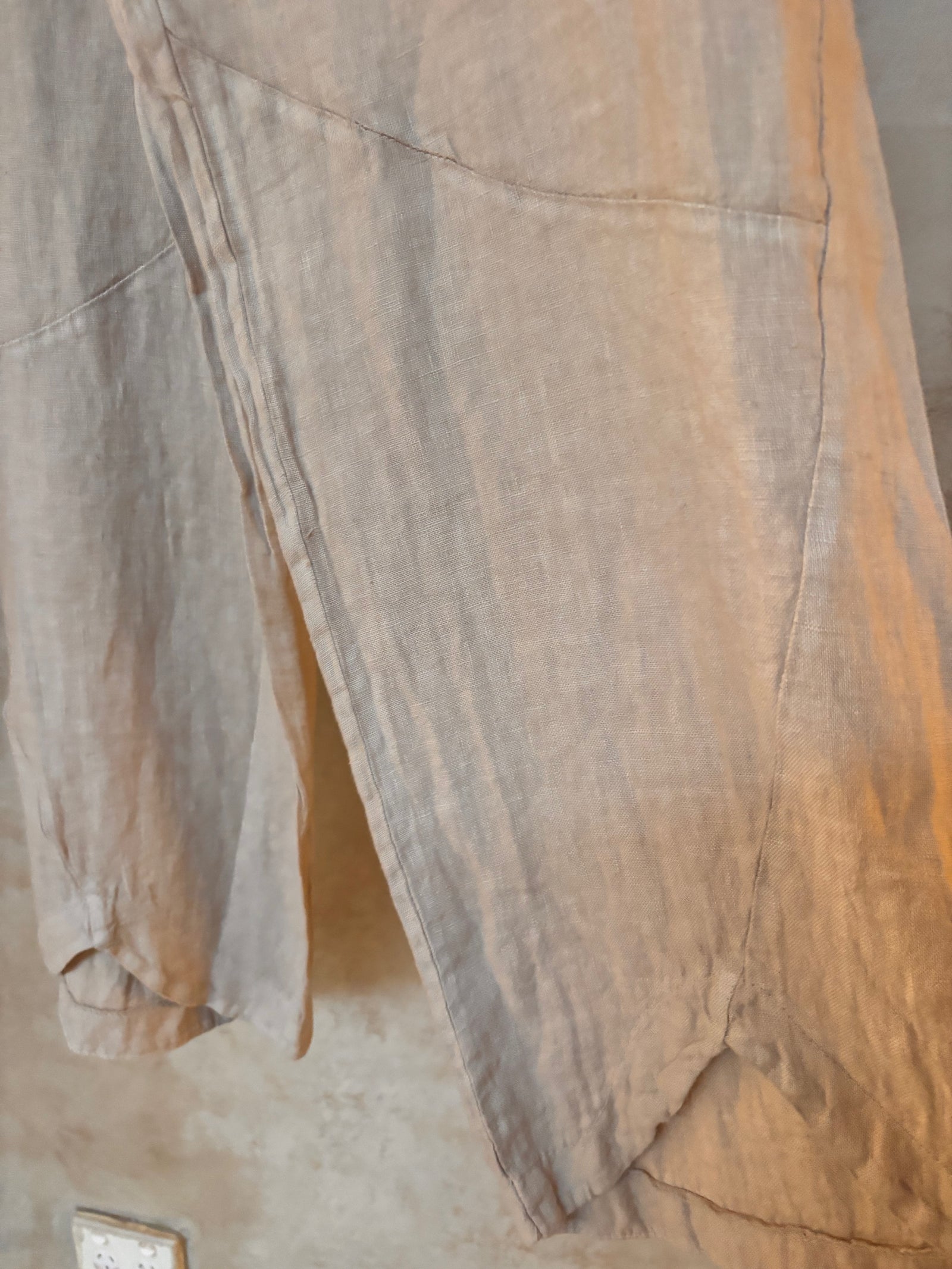 Close-up of a beige linen pants with a pocket on a neutral background