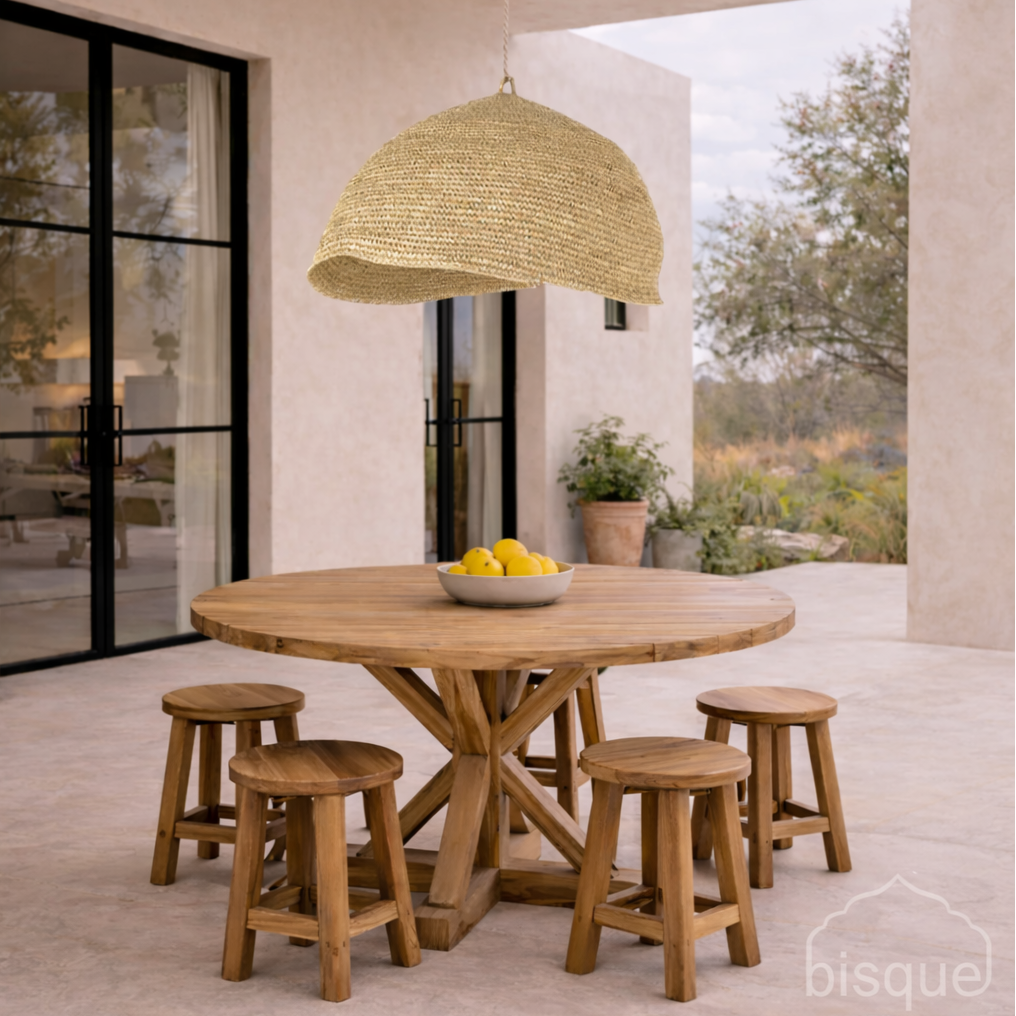 Wooden dining table with stools and a Bulan Raffia Pendant Light on a patio.