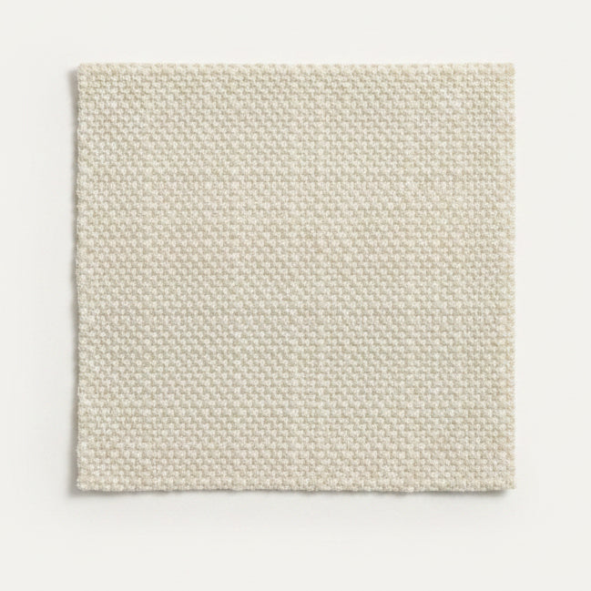 A square swatch of textured cream-colored woven fabric laid flat on a wooden surface.