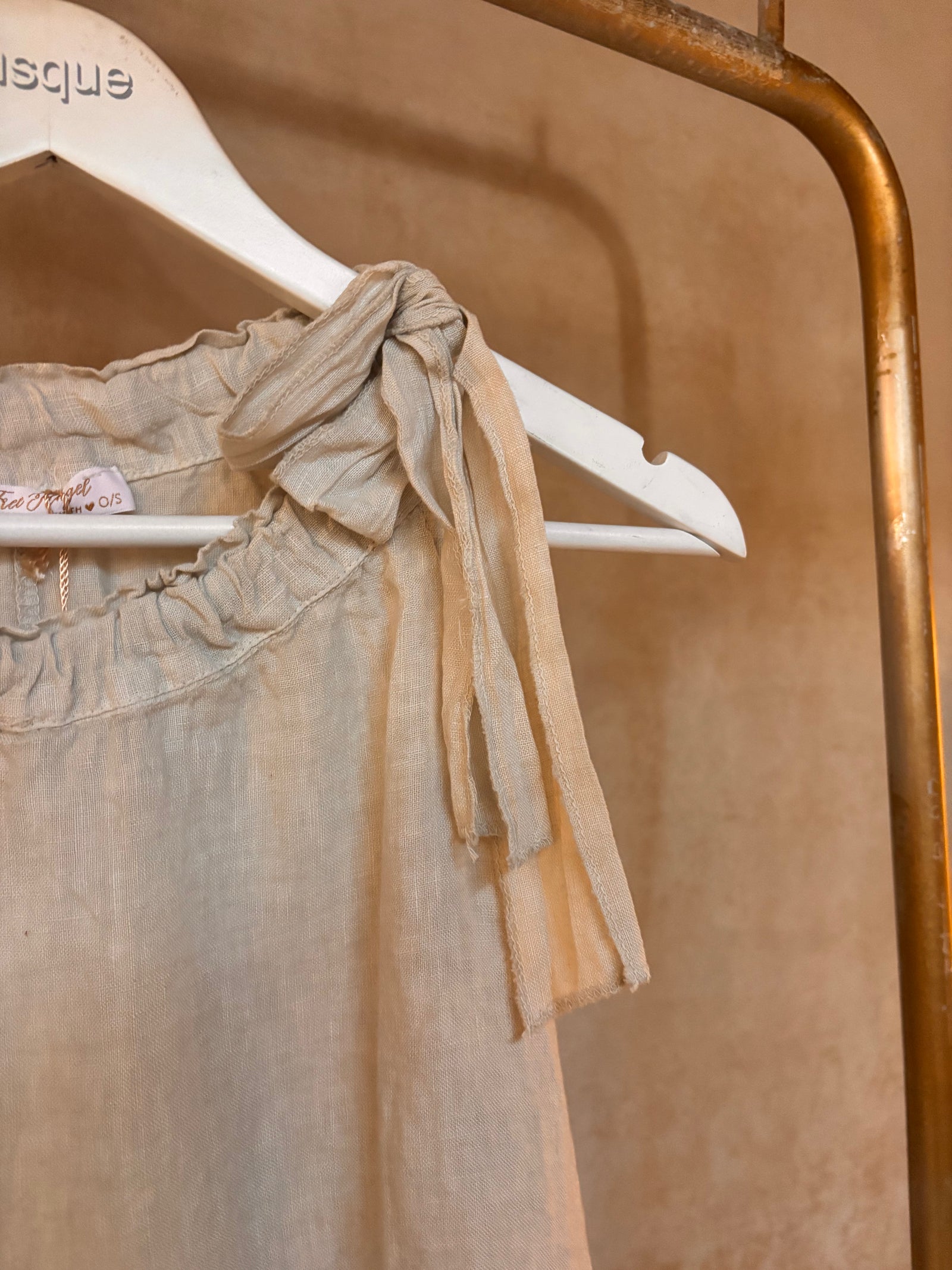 Beige Italian linen top with a bow tie on a white hanger