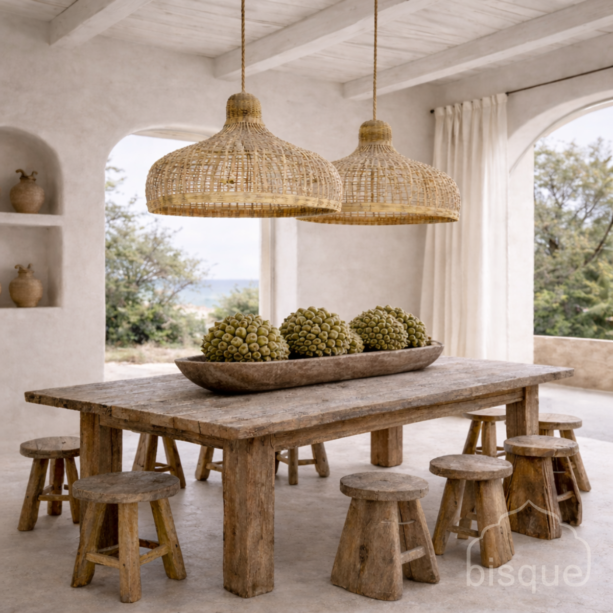 Dining area with wooden table and stools, featuring Laloma bamboo pendant lights.