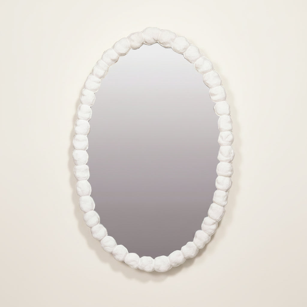 Oval mirror with a white bead frame on a light beige background