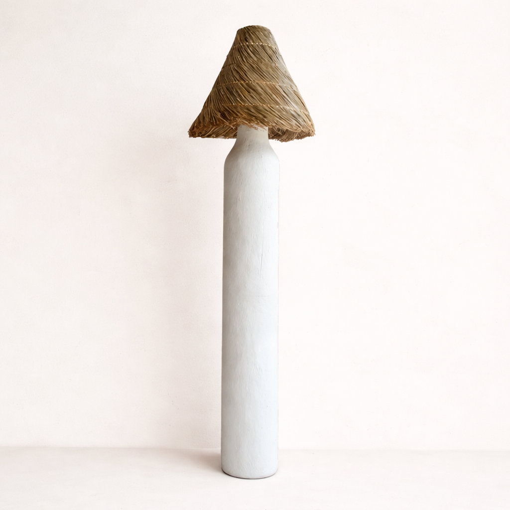White terracotta floor lamp with a rattan woven shade n a light background