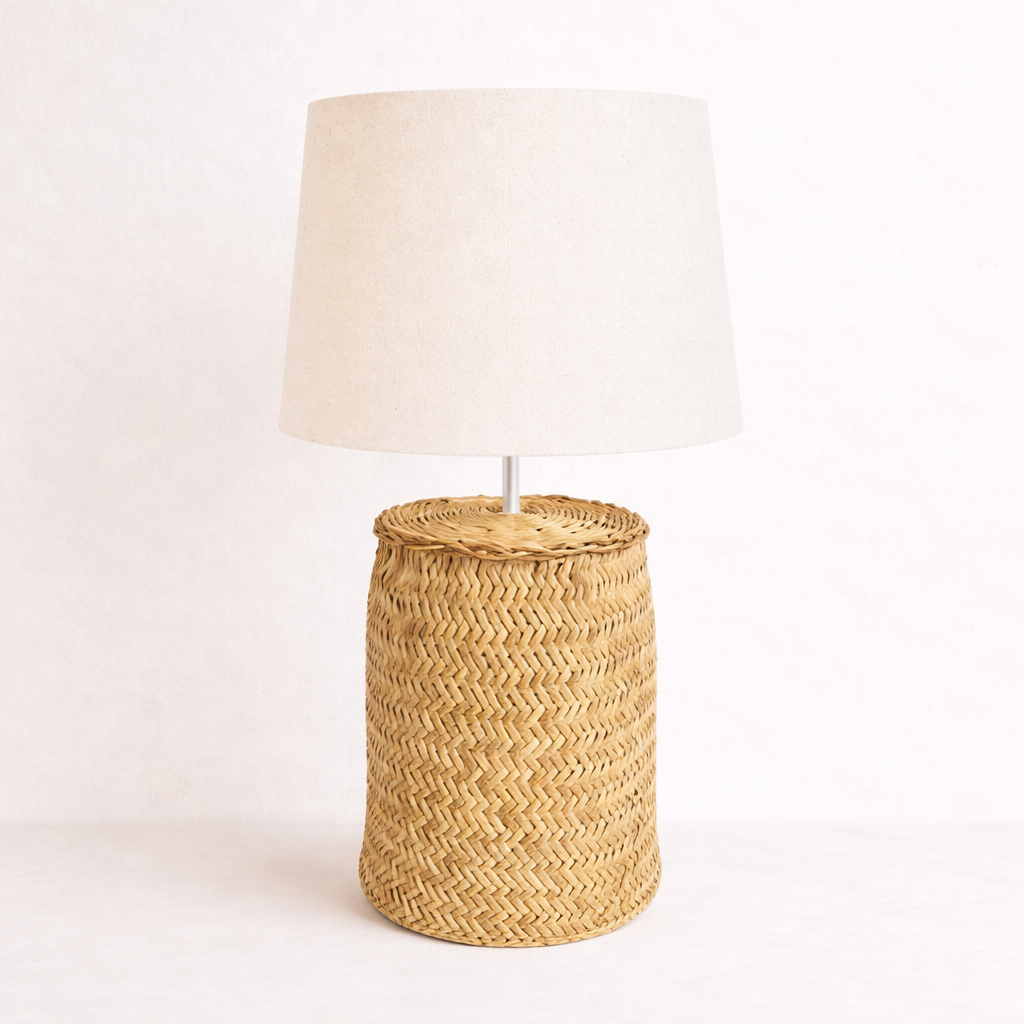 Lamp with wicker base and white shade on a light pink background