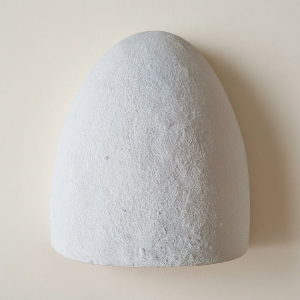 Dome-shaped white light fixture on a textured wall
