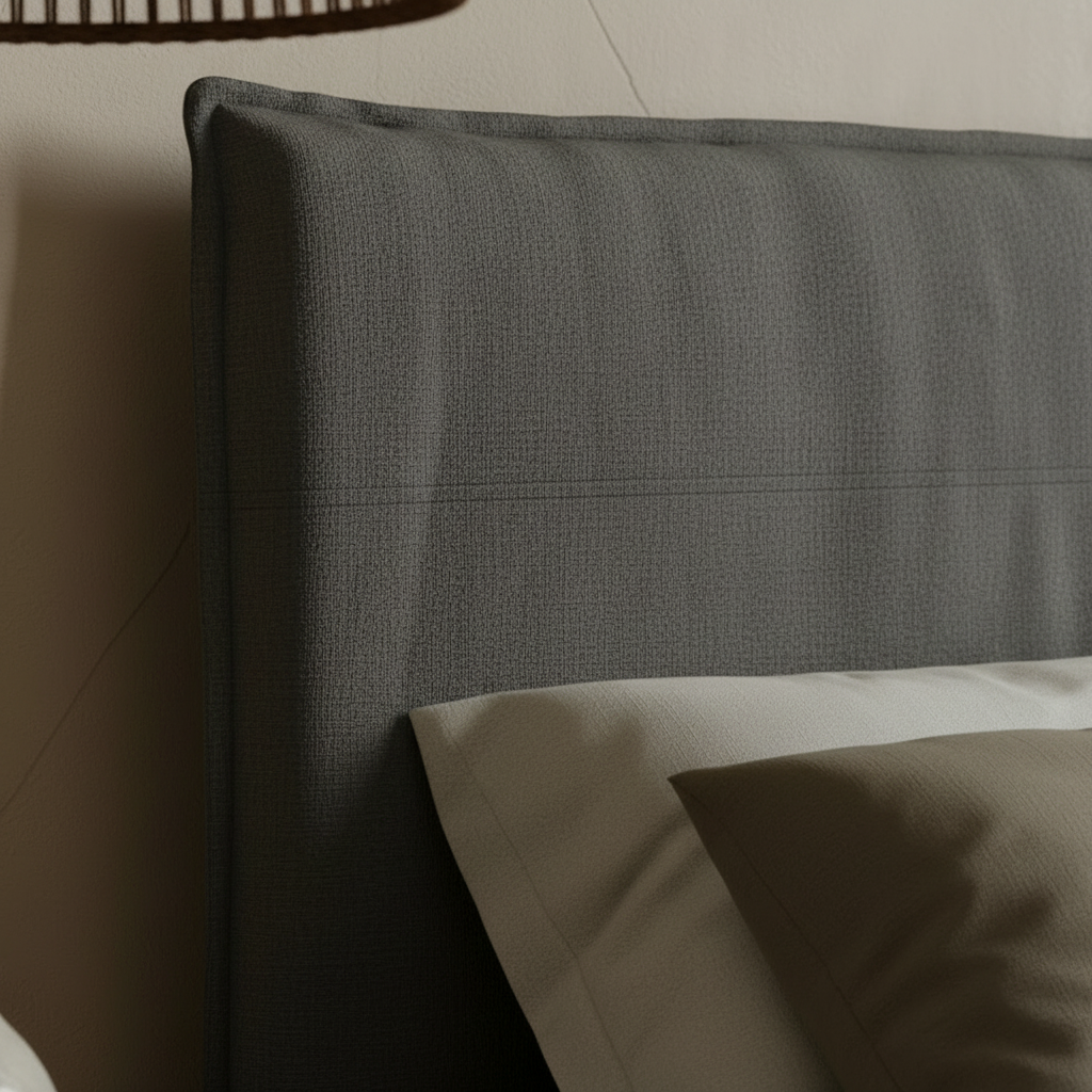 Neatly made bed with grey bedding in a bedroom setting.