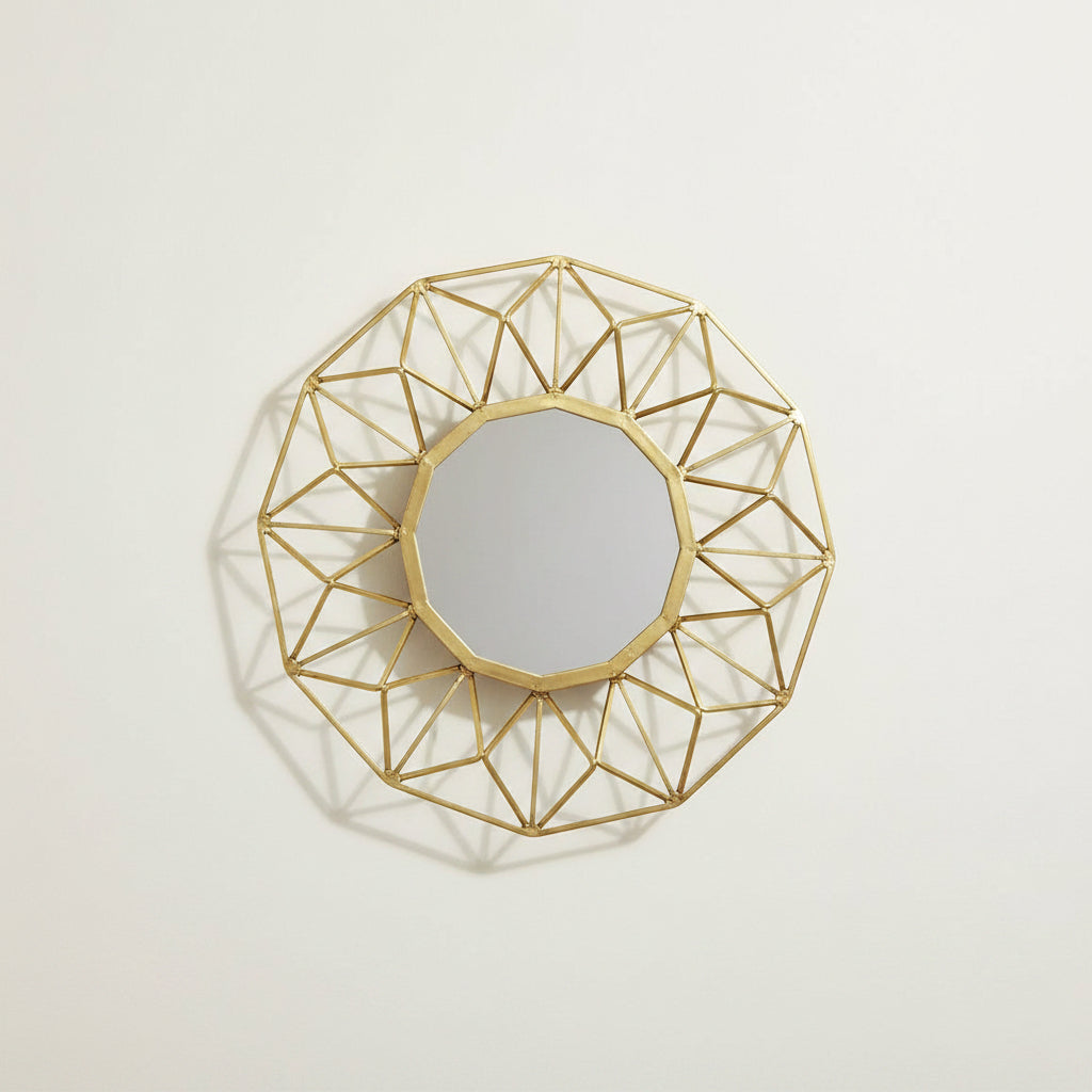 A round geometric wall mirror with an open, faceted gold metal frame and a reflective mirror center, shown on a plain white background.