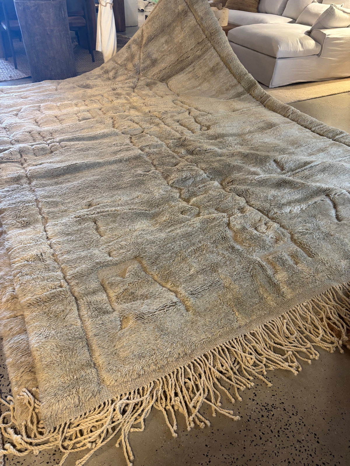 A hand-selected Moroccan Berber rug with a beige and green color palette, featuring intricate patterns and a tassel end.