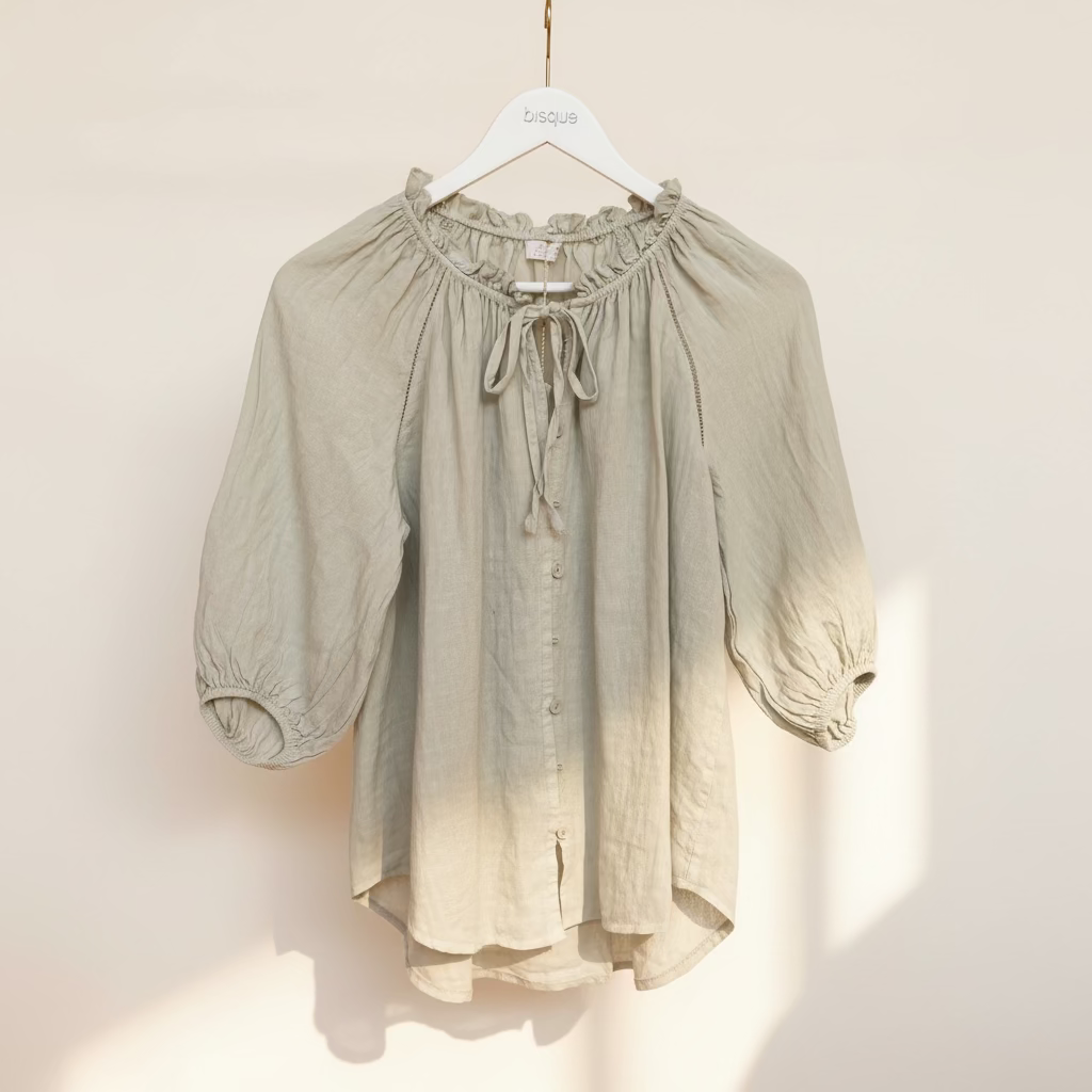 Light beige blouse on a hanger against a brown background