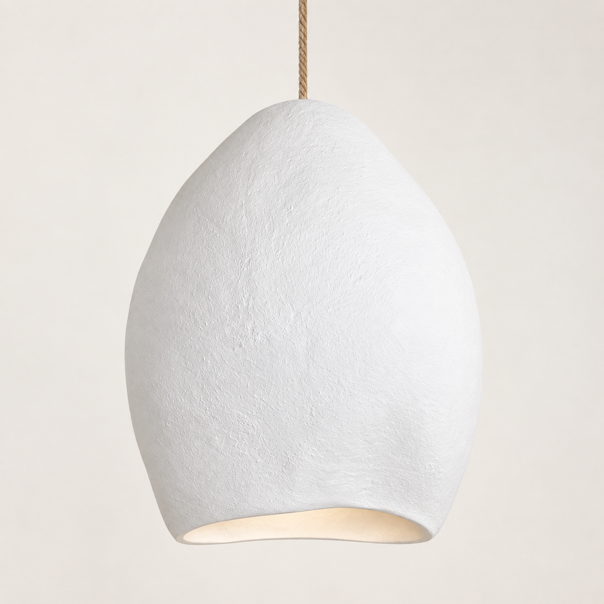A textured white ceramic pendant light shaped like a teardrop, suspended by a natural jute rope cord against a warm off-white background.