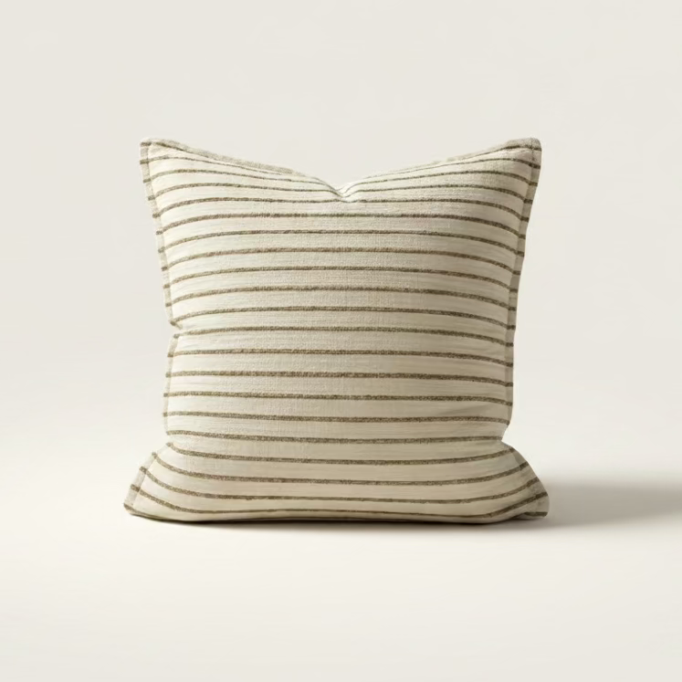 A striped cream and brown cushion with a textured design, displayed on a sofa, with decorative bowls on a shelf in the background.