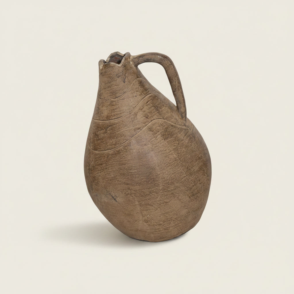 Brown ceramic pitcher on a textured beige wall