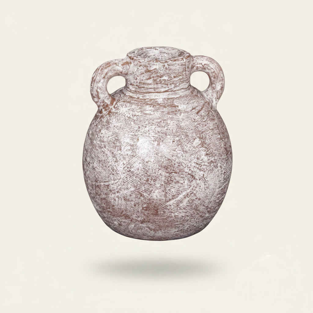 A rustic, round ceramic jug with two loop handles and a narrow neck, featuring a distressed finish with brown and white tones, set against a textured plaster wall.