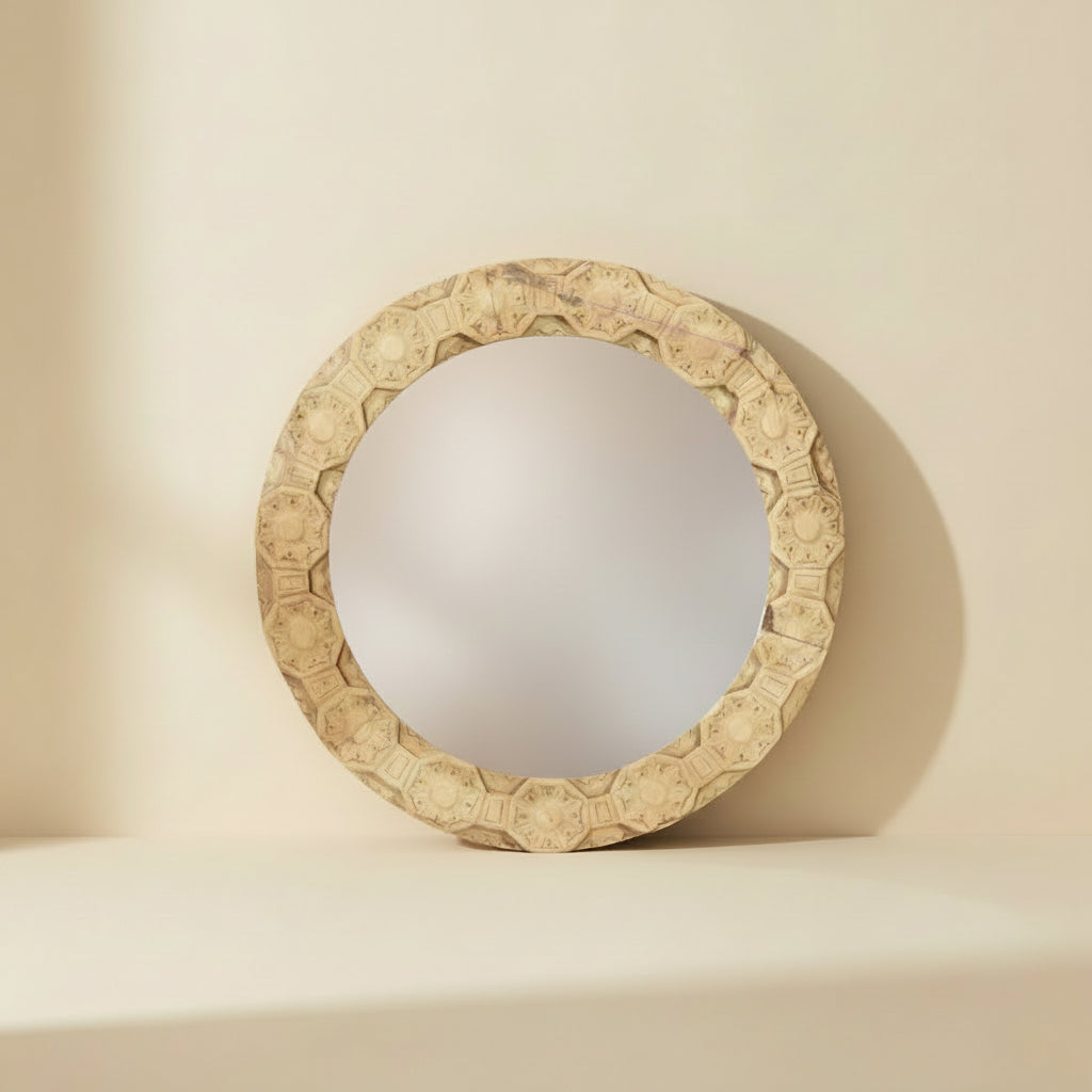 Round decorative mirror with an ornate carved beige frame featuring geometric and floral patterns, shown against a plain white background.