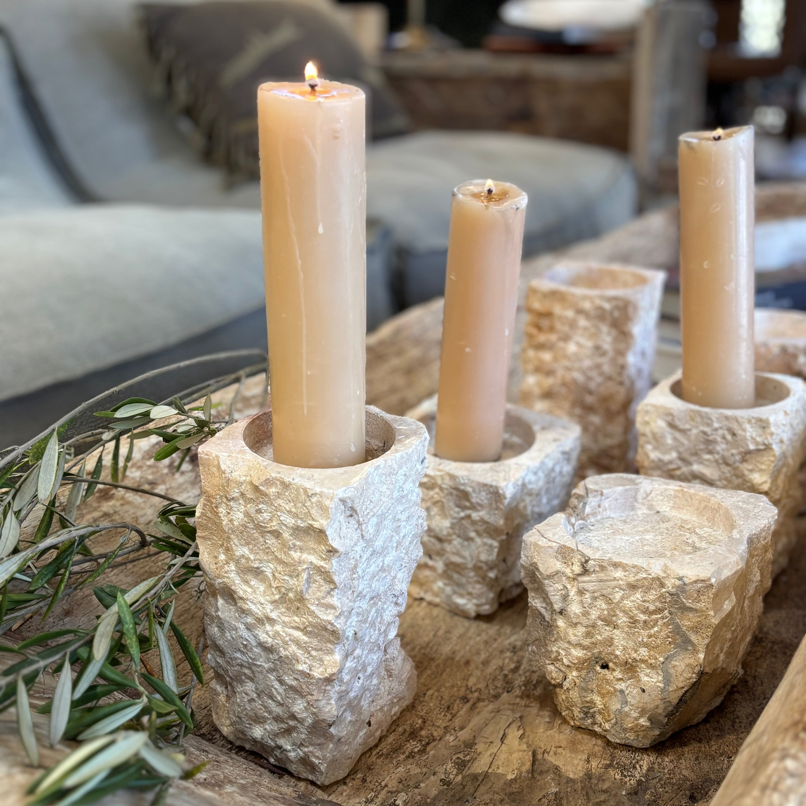 Decorative stone candle holders with candles on a wooden surface in a cozy living room.