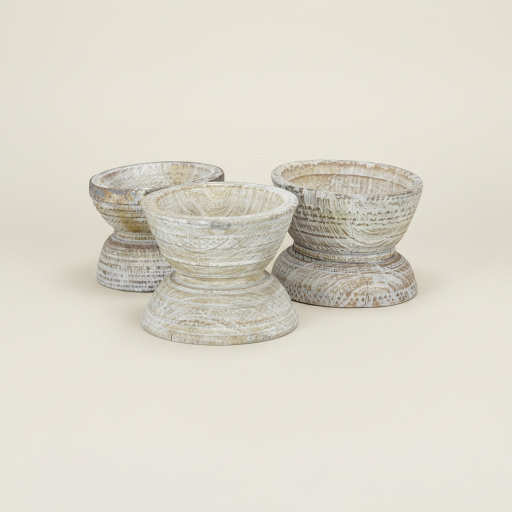 Three rustic distressed wood candle holders with a weathered gray and beige finish, arranged on a solid cream background.