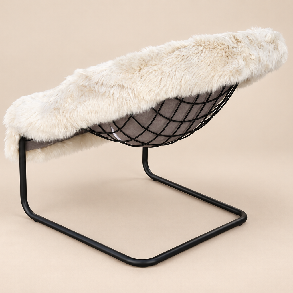 A modern wire chair with a black metal frame and a thick, fluffy off-white sheepskin or faux fur seat cover, set against a solid beige studio background.
