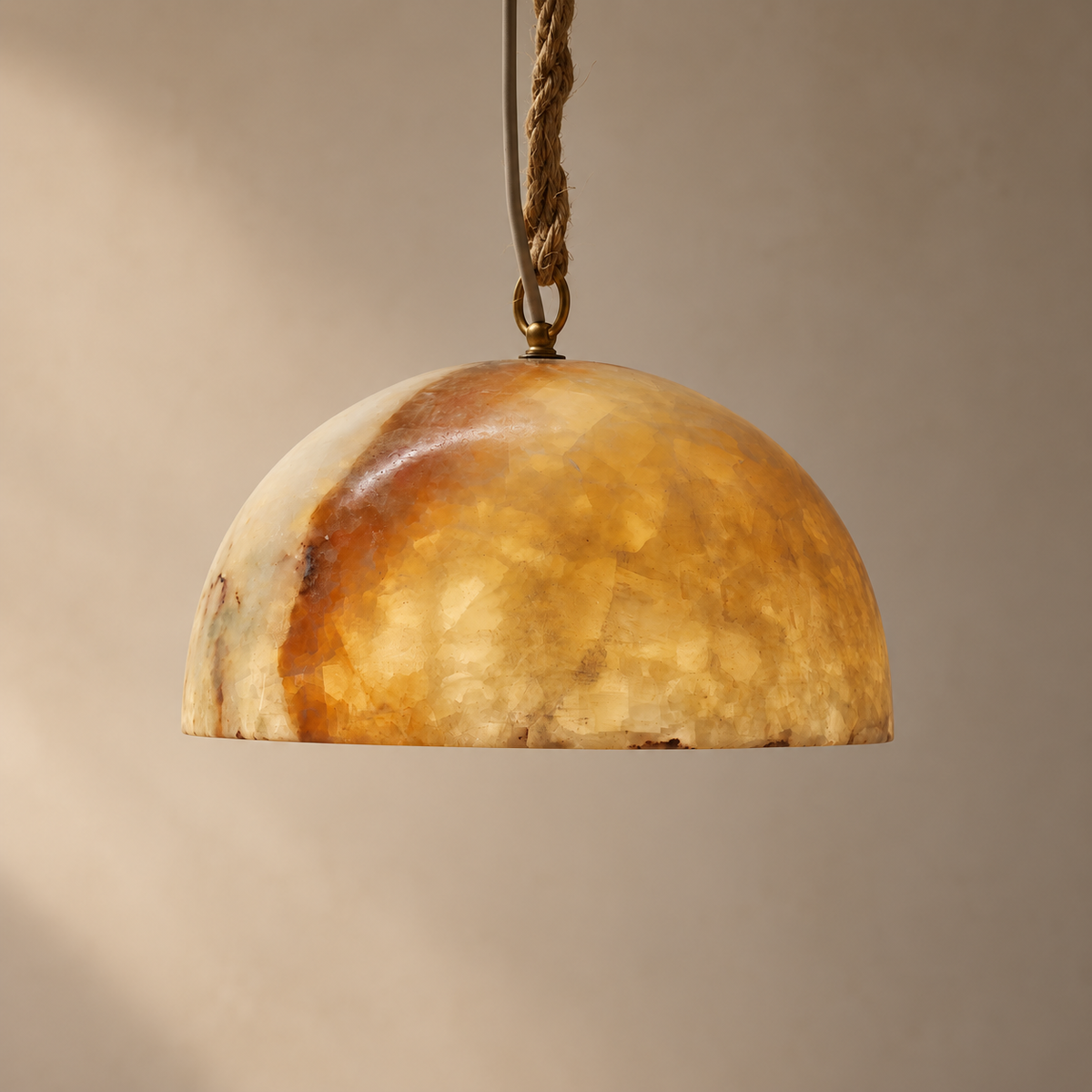 A dome-shaped pendant light shade made of textured, translucent amber glass or stone, suspended by a braided rope cord against a warm beige background.