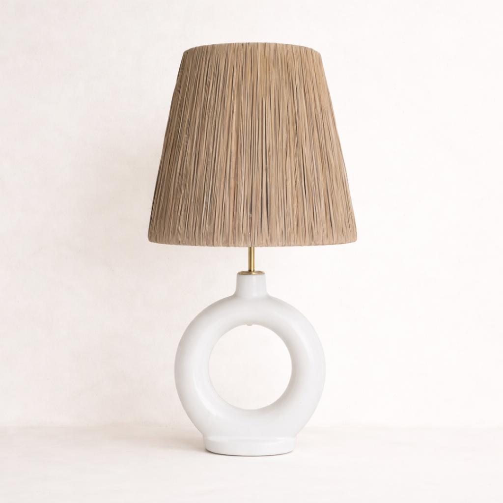 Table lamp with a white base and raffia woven shade on a light background