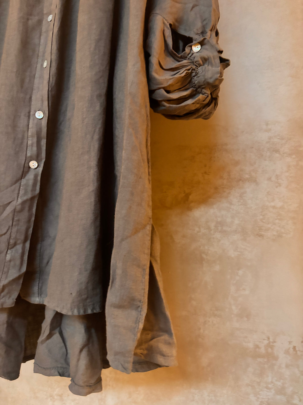 Dark brown coat with buttons on a textured beige background