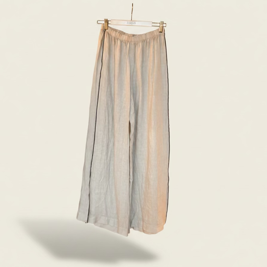 Pair of wide-leg Ariosa italian linen cream pants hanging on a wooden hanger against a plain background