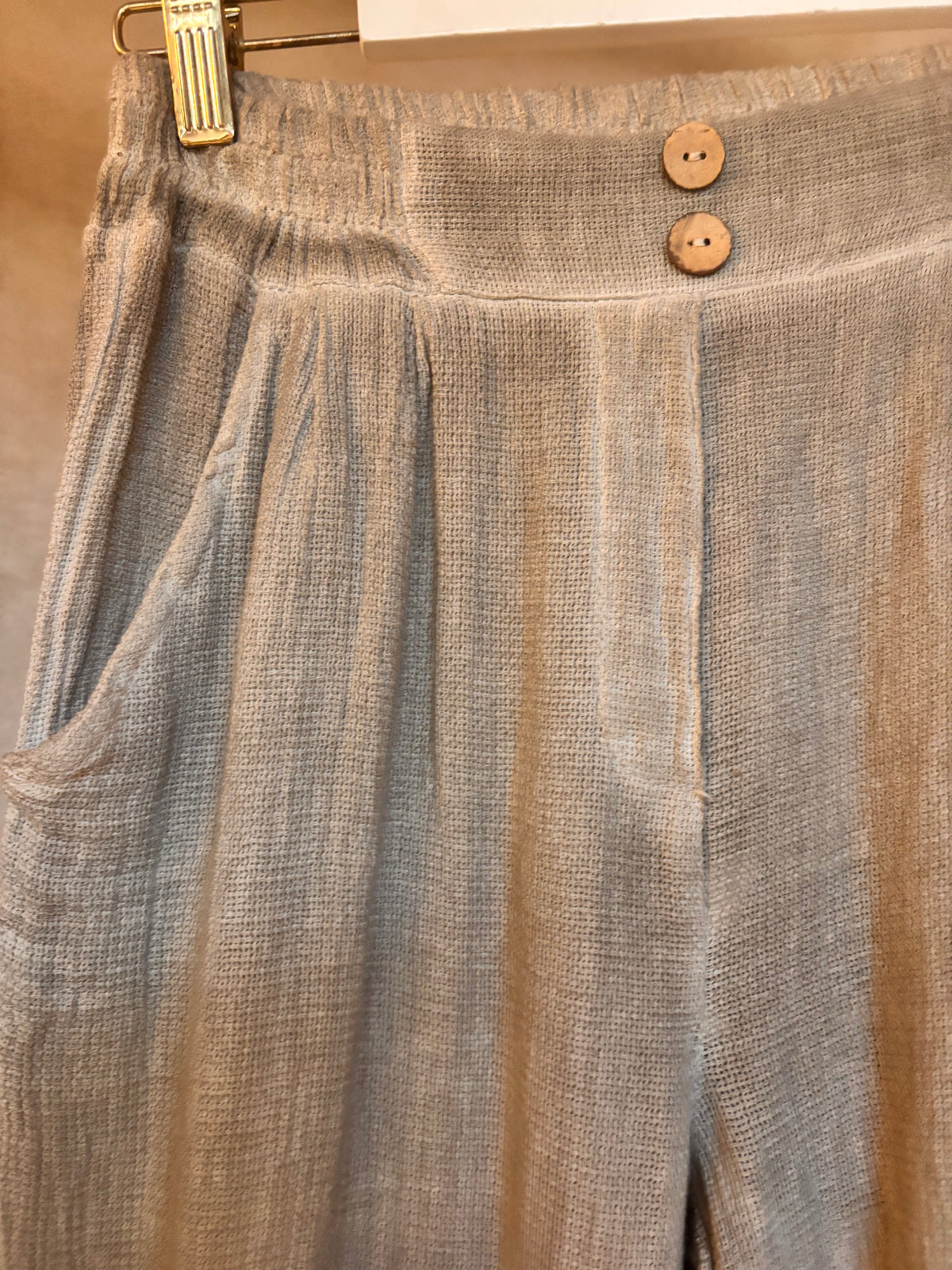 Brown textured pants with wooden buttons on a hanger