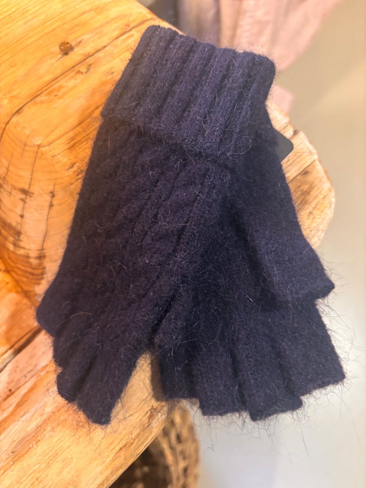 Pair of dark blue fingerless gloves on a wooden surface