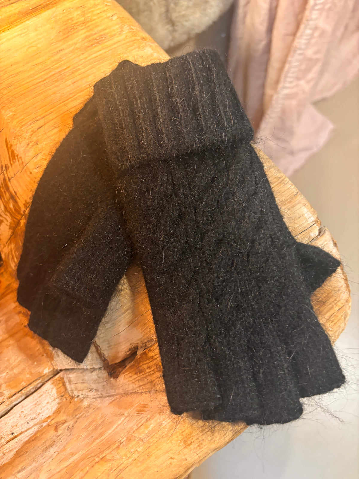Pair of black fingerless gloves on a wooden surface