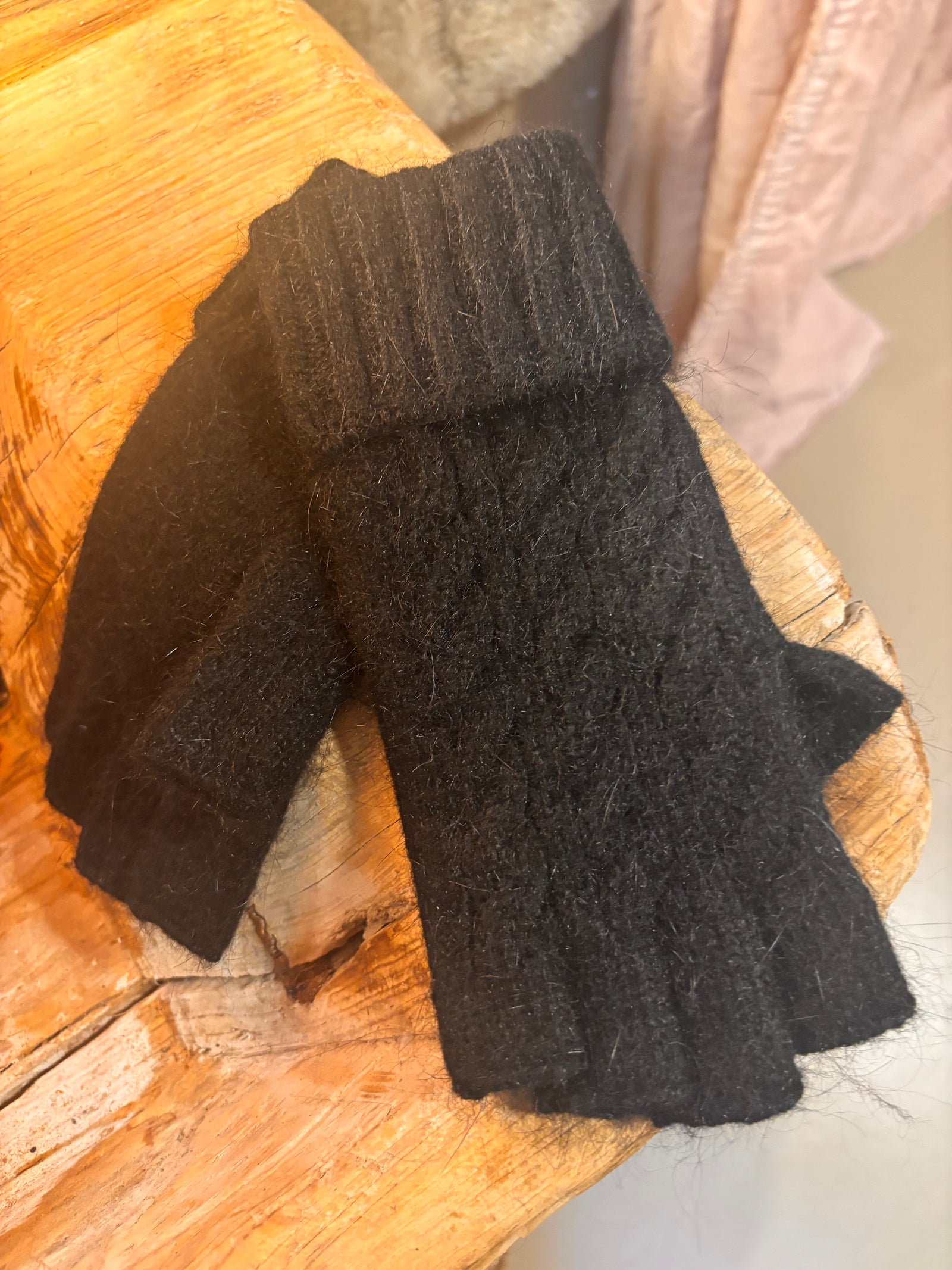 Pair of black fingerless gloves on a wooden surface