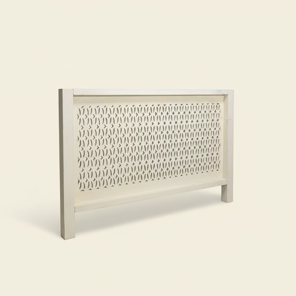 


Decorative carved wood white bedhead with intricate cut-out pattern on a wall.