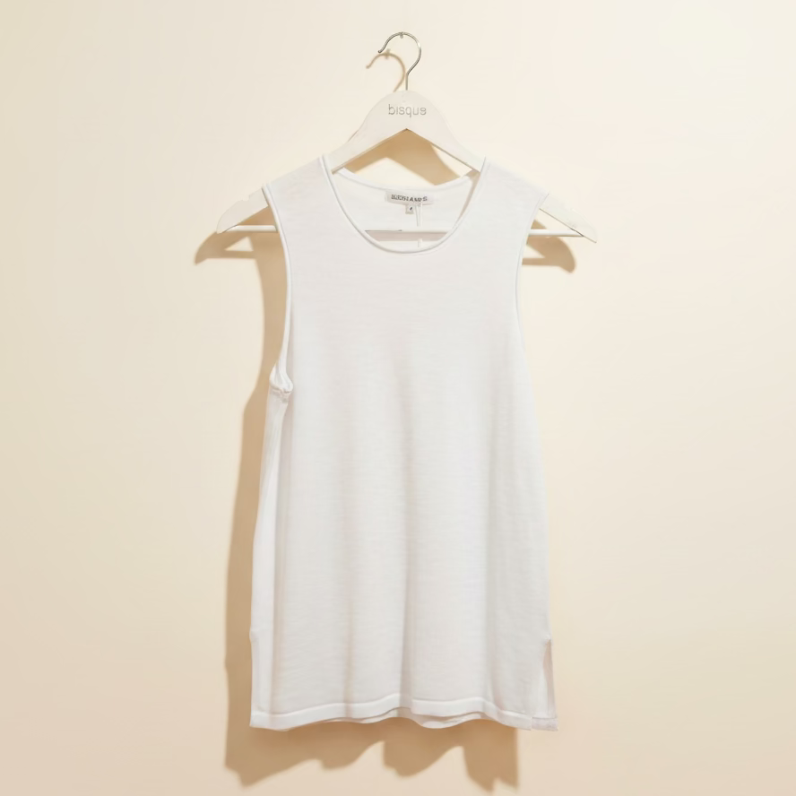 White cotton knit tank top on a hanger against a beige wall