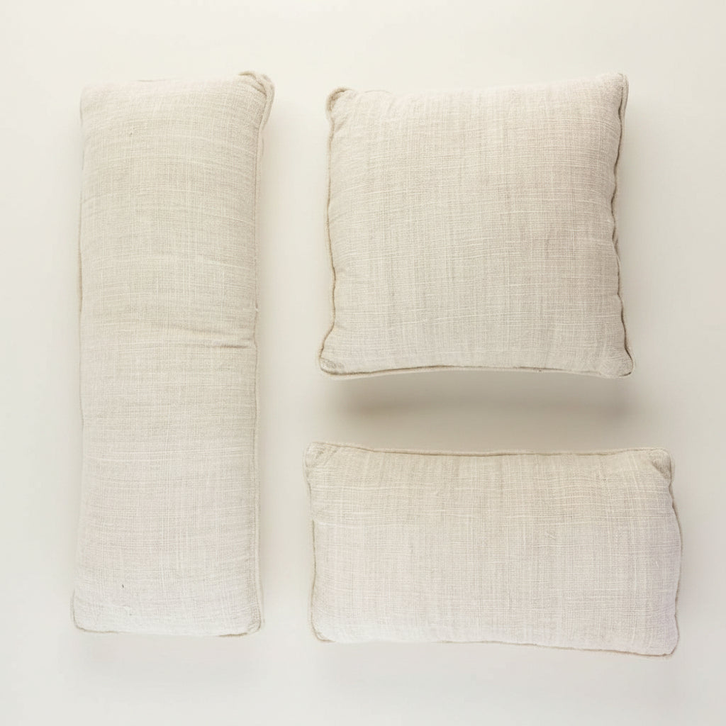 Set of three beige pillows on a textured white surface