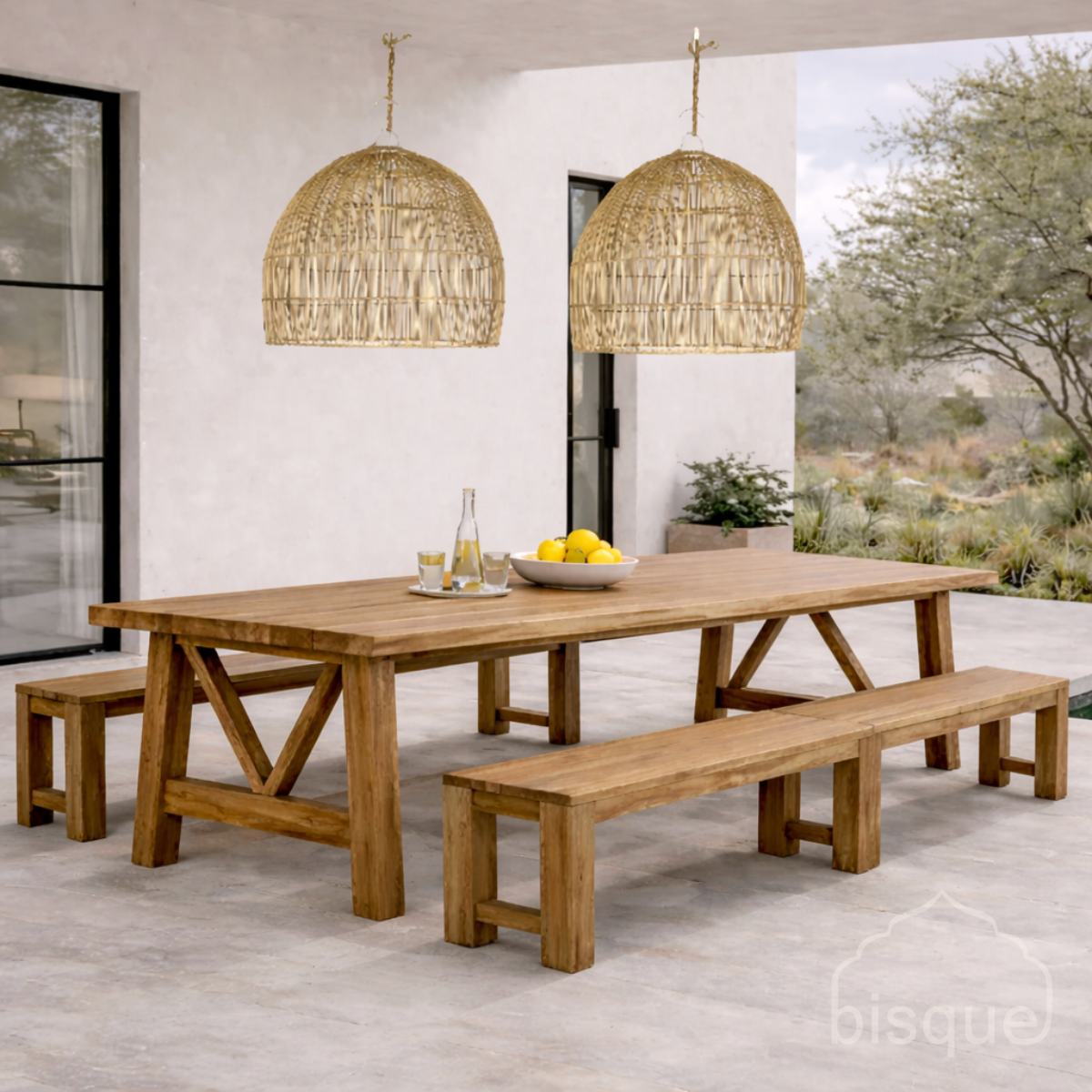 Wooden dining table with benches and Misozi Rattan pendant lights in an outdoor setting.