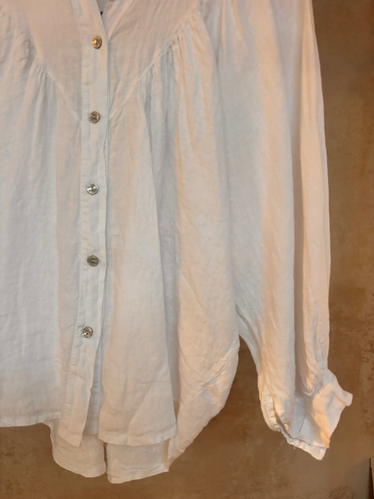 White button-up italian linen shirt with long sleeves on a beige background