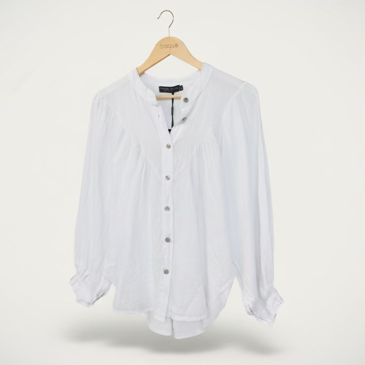 White italian linen blouse on a hanger against a brown background