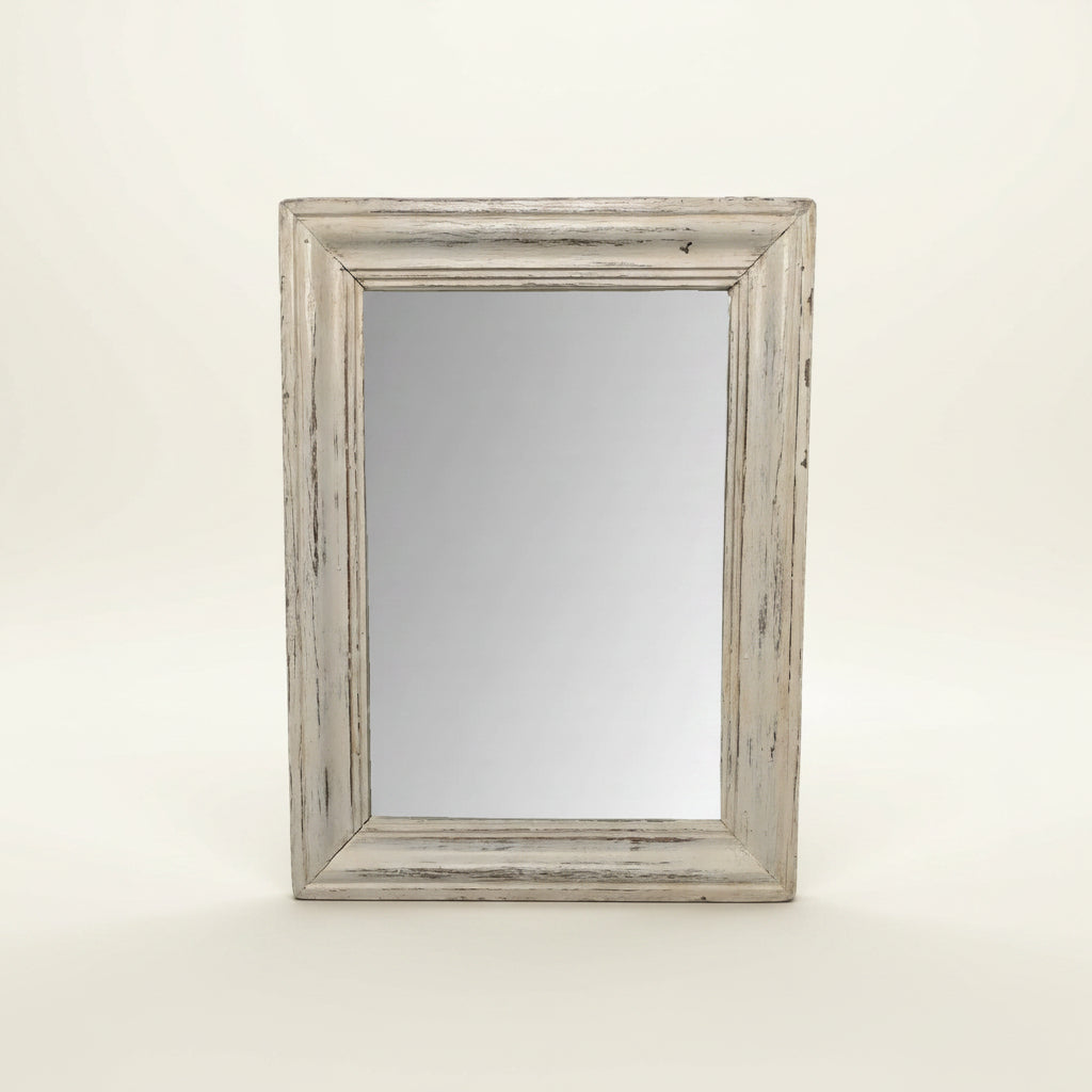 A rectangular wall mirror with a distressed, rustic white-painted wooden frame, standing upright against a plain off-white background.