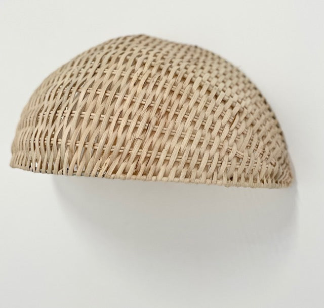 A beige rattan wall sconce with a unique, openwork design, displaying a natural and textured appearance.